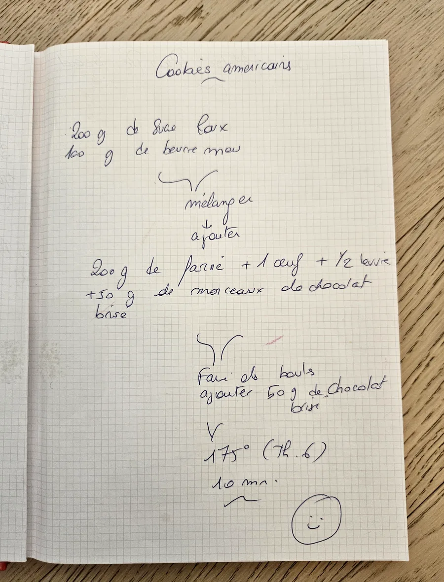 Un carnet ouvert sur une table, la recette des cookies écrite à la main